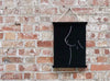 Black nude sketch art in a magnetic print hanger on a brick wall