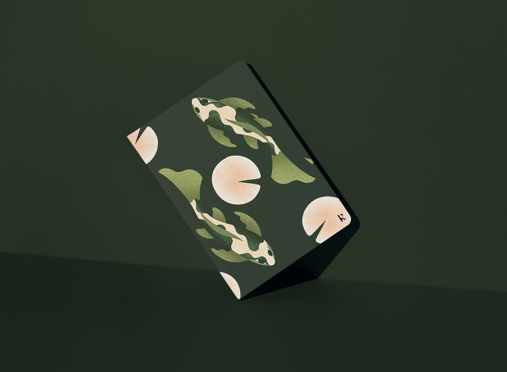 Julie Solvstrom limited edition Karst hardcover notebook shown at an angle with illustrated koi fish design on a deep green background.