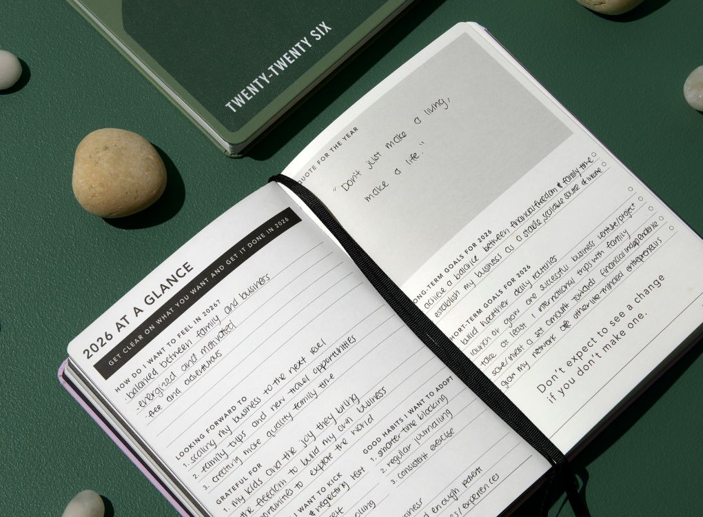 From Little Things 2026 Weekly Spread Diary open on 2026 review page against green background surround by stones and 2026 Weekly Notes diary.