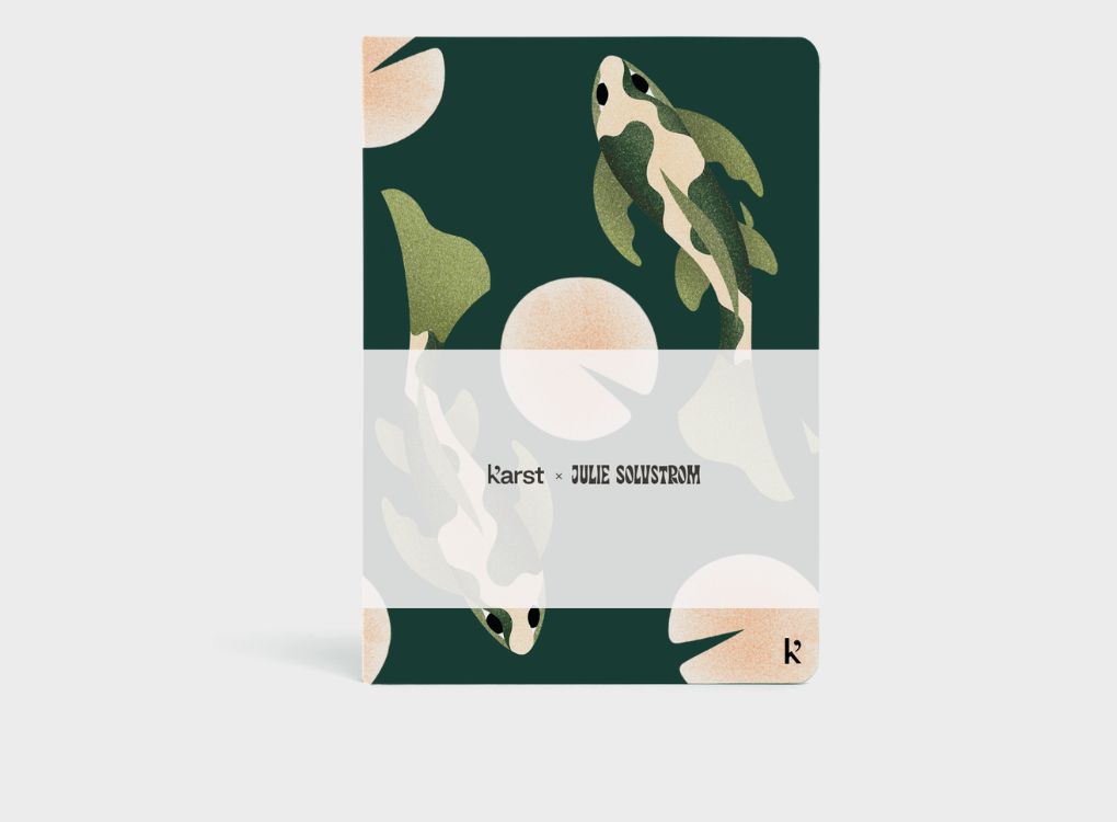 Julie Solvstrom limited edition Karst hardcover notebook shown at an angle with illustrated koi fish design on a deep green background.