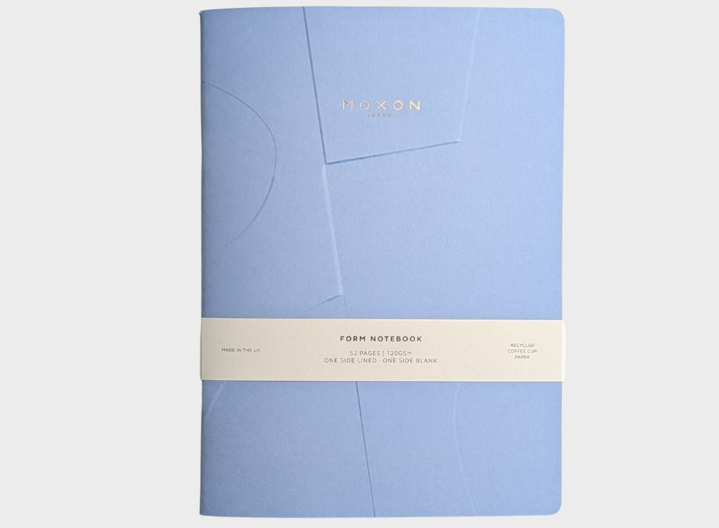 Blue MOXON B5 ‘Form’ notebook with packaging band on a clean neutral background