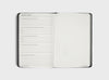 MiGoals 2026 Classic Diary monthly review spread with reflection prompts for accomplishments, progress on goals, upcoming challenges, and a blank dotted page for notes or mind mapping.