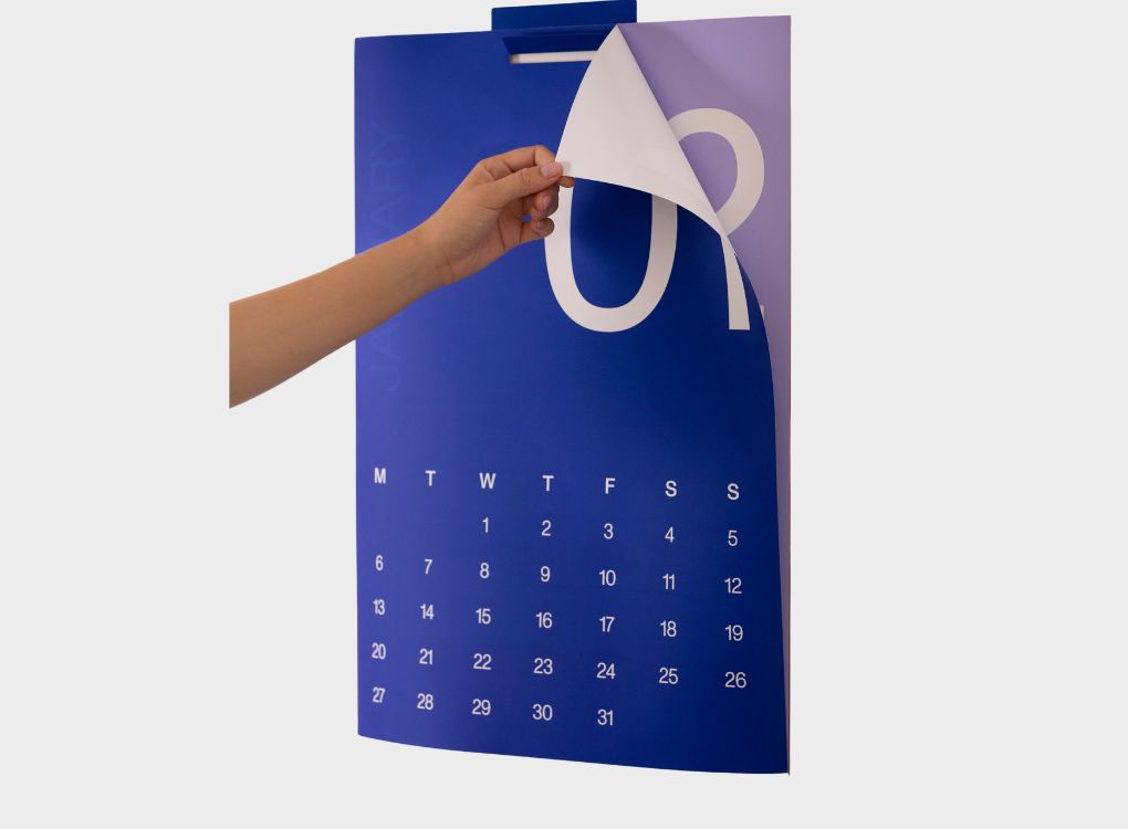 Karst 2026 A2 Monthly Calendar with a hand flipping from January to February, displaying bold white numerals against a blue background.