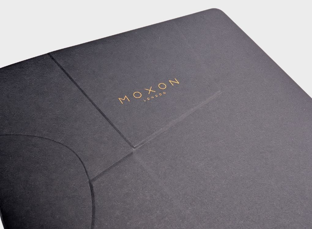 Close-up of black MOXON B5 ‘Form’ notebook cover showing embossed design and gold logo