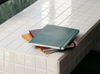 Karst stone paper B5 undated planners in turmeric, burgundy, and forest stacked on a table.