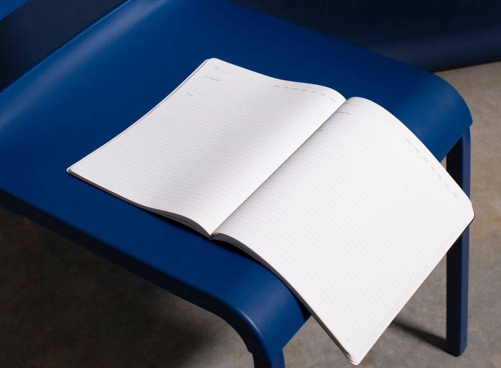 Olive green Karst notebook with a vegan leather soft cover laying on a metal bench