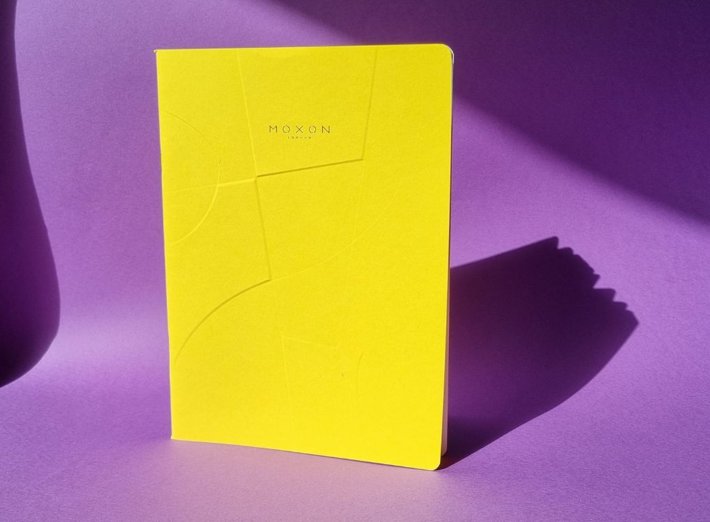Yellow MOXON B5 ‘Form’ notebook standing upright on a purple surface with strong shadow