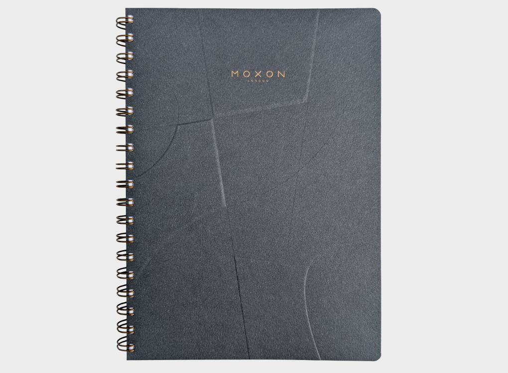 Wire-bound B5 daily planner with a dark navy recycled cover, blind-embossed with a geometric ‘Form’ pattern and subtle gold foil ‘MOXON’ logo.
