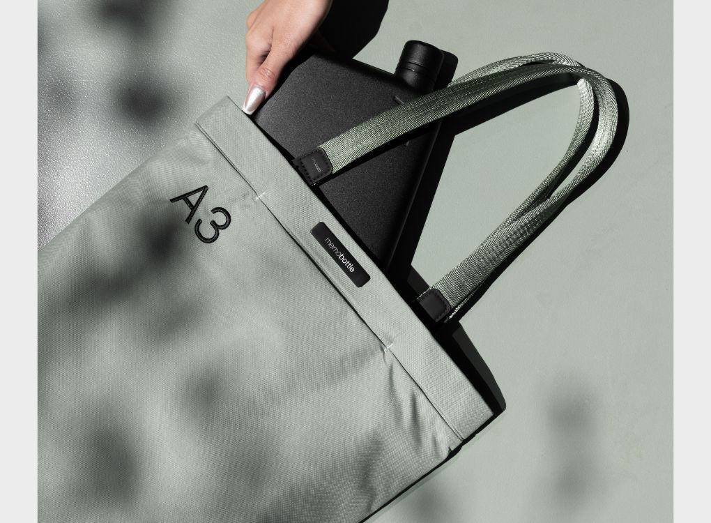 Woman putting Memobottle in A3 Eucalypt Tote Bag.
