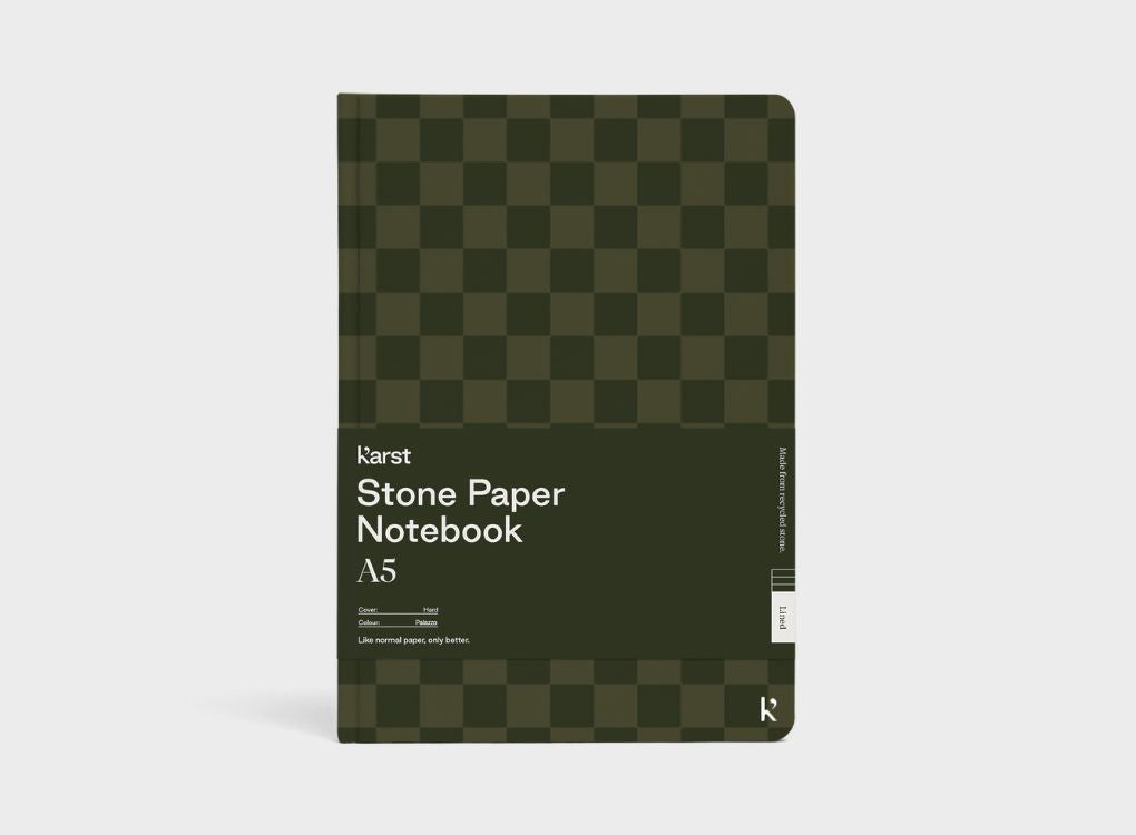 A Studio Muse A5 hardcover notebook by Karst with a dark olive green checkerboard patterned cover, displayed against a plain white background. The notebook features smooth, recycled stone paper with lined pages and a slim, lightweight cover.