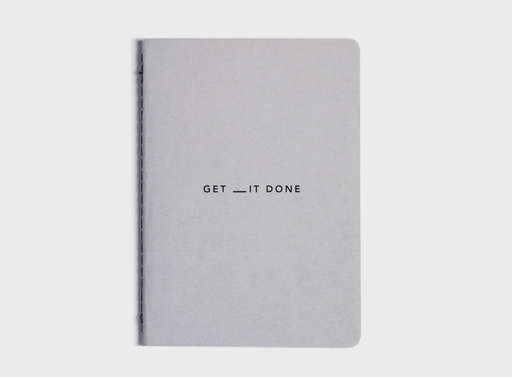 MiGoals Get It Done motivational notebook in light grey and black on a grey background. A versatile notebook designed to motivate you.