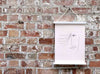 Contemporary Face Art sketch art in a white magnetic print hanger on a brick wall